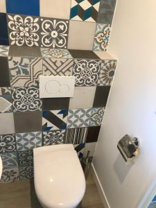 a bathroom with a toilet and a tile wall at Villa patio terrasse privative océan 10 min a pied in Seignosse
