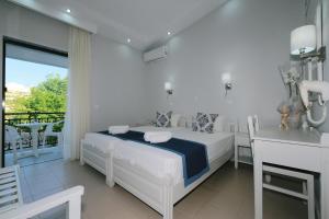 a white bedroom with a bed and a balcony at Ifestos Hotel in Myrina