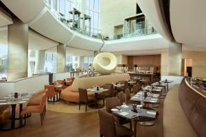 a restaurant with tables and chairs in a building at Millennium Al Rawdah Hotel in Abu Dhabi