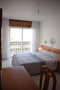 a bedroom with two beds and a large window at Apartamentos O Grove in O Grove