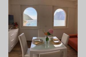 a dining room with a table and two windows at Wind Rose Apartments 2 in Nago-Torbole