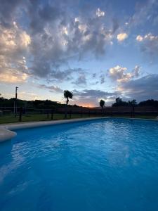 a large blue swimming pool with a sunset in the background at complejo rural el prado in Logrosán