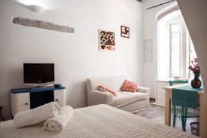 a white room with a bed and a tv and a couch at B&B LE TRE CHIOCCIOLE in SantʼAntìoco