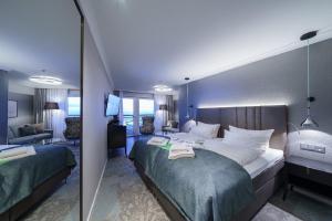 Habitación de hotel con 2 camas y sala de estar. en Strandhotel Duhnen, en Cuxhaven