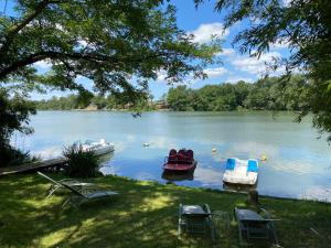 two boats on a lake with two chairs at Gite Les Buis de Saint Martin in Marssac-sur-Tarn