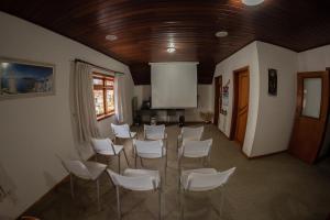 een conferentieruimte met witte stoelen en een scherm bij Pousada Alto D'ouro in Campos do Jordão