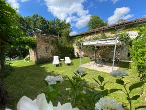 ogród ze stołem i krzesłami oraz budynek w obiekcie Gite Les Buis de Saint Martin w mieście Marssac-sur-Tarn