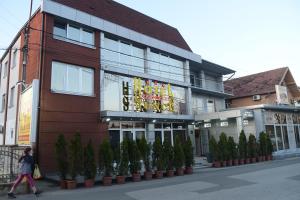 a woman walking past a building with a sign on it at Hotel Sunce in Kraljevo