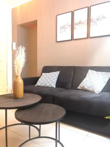 a living room with a black couch and two tables at Studio Vieil Antibes - Saint Antoine in Antibes