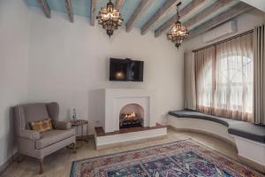 a living room with a fireplace and a chair and a tv at Casa Delphine in San Miguel de Allende