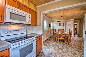 een keuken met een fornuis, een magnetron en een tafel bij Cottage with Deck and Yard 2 Mi to Dale Hollow Lake! in Byrdstown