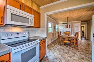 a kitchen with a stove and a microwave and a table at Cottage with Deck and BBQ 2 Mi to Dale Hollow Lake! in Byrdstown