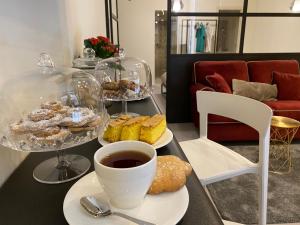 un tavolo con piatti di prodotti da forno e una tazza di caffè di Suite Cagliari -99- a Cagliari