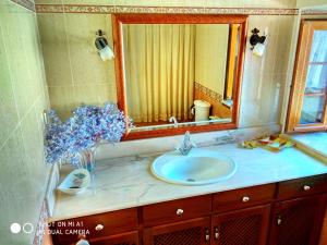a bathroom sink with a mirror and a vase of flowers at CASA AMPLIA CON JARDÍN Y APARCAMIENTO G-100147 in Ajo +19 photos