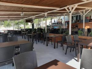 an empty restaurant with wooden tables and chairs at Petani Beachside Accommodation in Vóvikes