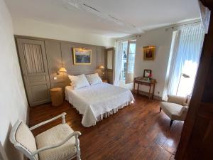 sypialnia z białym łóżkiem i 2 krzesłami w obiekcie Gite De Charme Au Bord Du Tarn w mieście Marssac-sur-Tarn