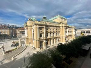 un grand bâtiment jaune avec un toit vert dans l'établissement Plaza Teatro & Piazzale Teatro, à Rijeka