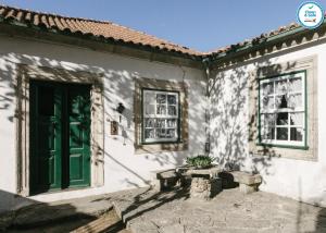 un edificio bianco con una porta verde e una panchina di Casa da Tapa 7 a Vila Pouca de Aguiar