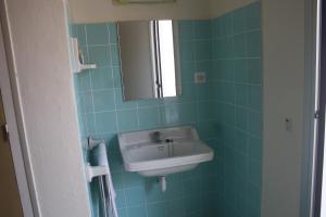 Baño de azulejos azules con lavabo y espejo en Hostal Torre Mar, en Salou