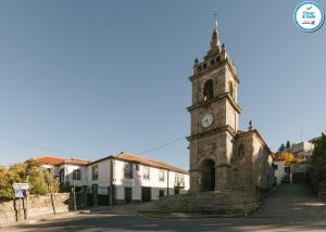 un vieux bâtiment avec une tour d'horloge dans une rue dans l'établissement Casa da Tapa 7, à Vila Pouca de Aguiar