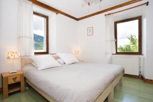 une chambre blanche avec un grand lit avec deux fenêtres dans l'établissement Gite-Auberge de Montvilliers, à Aime