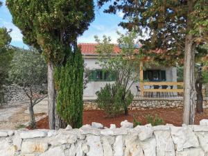 ein Haus hinter einem Steinzaun mit einer Steinmauer in der Unterkunft Kuća za odmor obitelji Pedišić in Banj
