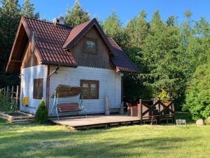 a small white house with a wooden deck at Pod Papugami in Laskowice