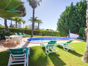 a yard with chairs and a pool and a table at Modern villa in an exclusive residential area with a private swimming pool in Vilamoura