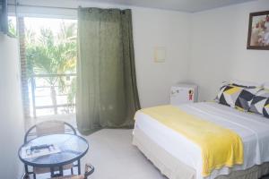a bedroom with a bed and a table and a window at Pousada Paraíso das Palmeiras in Paripueira