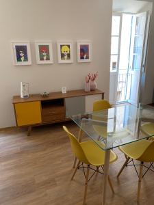 een eetkamer met een glazen tafel en gele stoelen bij Dimora D'Este in Tivoli