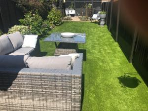 eine Terrasse mit Gras, einer Couch und einem Tisch in der Unterkunft Victorian Cottage in Deal