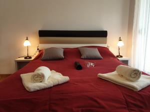 een slaapkamer met een rood bed en handdoeken erop bij Happy in Vrnjačka Banja