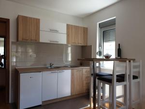 eine Küche mit weißen Schränken, einem Tisch und einem Waschbecken in der Unterkunft Happy in Vrnjačka Banja