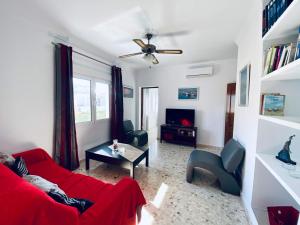 uma sala de estar com um sofá vermelho e uma televisão em Ramón y Cajal 6 em Chipiona