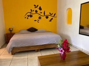 een slaapkamer met een bed en een tafel met bloemen bij Ximena Studios in Sayulita