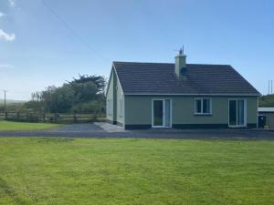 a green house with a grass field in front of it at Gurraun House in Kilkee