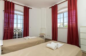 two beds in a room with red curtains at Albuera Villa in Albufeira