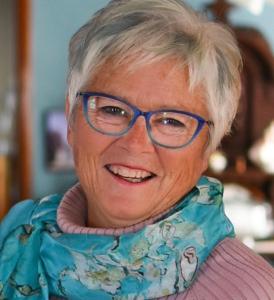 an older woman wearing glasses smiles at the camera at Bondy House Bed & Breakfast in Amherstburg