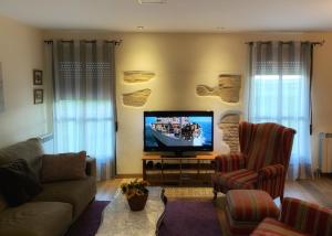 uma sala de estar com uma televisão, um sofá e uma cadeira em Casa Justo em Apiés
