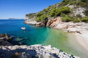 a boat in the water next to a beach at The Sea House Apartments in Vis