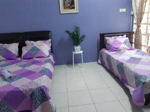 Habitación púrpura con 2 camas y maceta en Anis Homestay Bangi, en Bangi