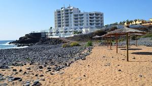 una playa con sombrillas y un edificio de fondo en Exclusively located Golf Villa with heated pool, en San Miguel de Abona