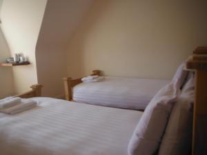a bedroom with two beds with white sheets at Inspiration Lodge in Anascaul