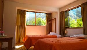 a hotel room with two beds and two windows at Tambo de Ollantay Hotel in Ollantaytambo