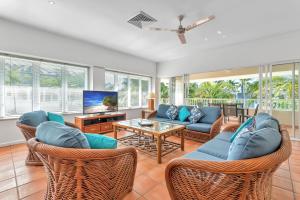 a living room with wicker furniture and a tv at Balboa Apartments in Port Douglas