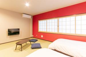 a bedroom with a red wall and a bed and a table at Wa no Kaede in Tokyo