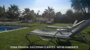un gruppo di sedie sedute sull'erba a bordo piscina di Villa Capricho de Luna a Caparacena