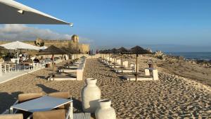 a beach with chairs and tables and umbrellas at Casa Oliveira in Vila do Conde