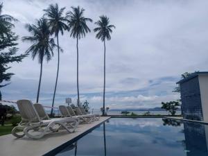 a swimming pool with chairs and palm trees at Rafflesia Resort in Lundu