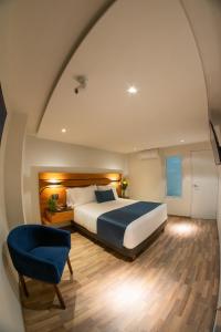 ein Schlafzimmer mit einem Bett und einem blauen Stuhl in der Unterkunft Hotel Boutique Maria in Morelia